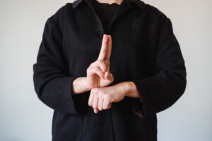 man in a black coat showing a sign in a sign language